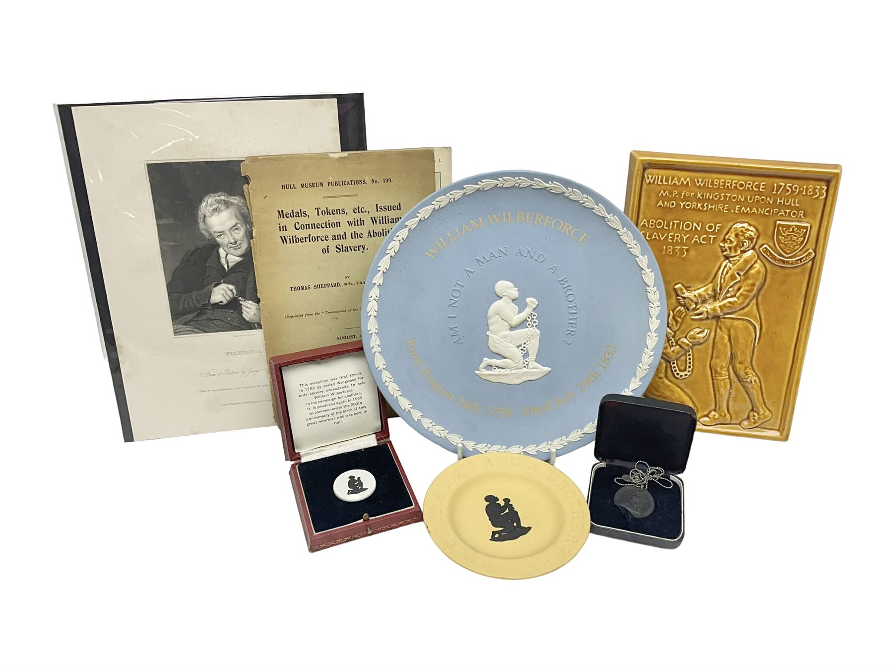 Group of William Wilberforce Abolition of Slavery items, comprising Wedgwood black on cane Jasperware pin tray, Wedgwood light blue Jasperware plate, and two Wedgwood oval medallion pendants, each depicting a kneeling figure beneath the inscription 'AM I NOT A MAN AND A BROTHER?', an Eastgate pottery plaque decorated in relief with a kneeling figure before William Wilberforce, a Hull Museum Publications pamphlet titled 'Medals, Tokens, etc., Issued in Connection with William Wilberforce and the Abolition of Slavery', by Thomas Sheppard, dated 1916, and an antique print depicting William Wilberforce after the original portrait by George Richmond, (7)