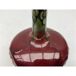 Three Minton Secessionist vases, with tube-lined stylised flower decoration, two upon a red ground and third upon a purple ground, all with printed mark to base 'Minton Ltd, No. 33', H13cm