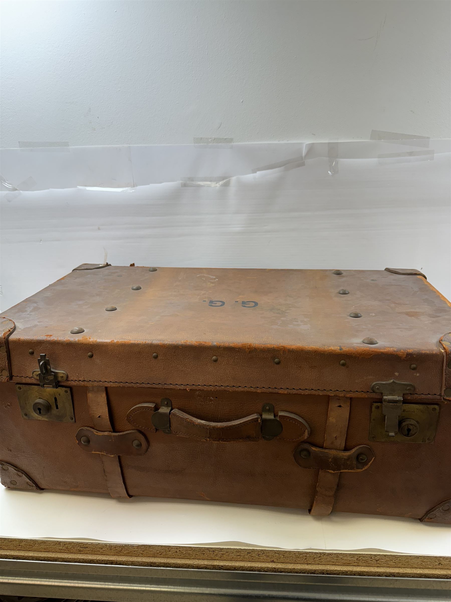 Early 20th century leather trunk, with brass fixtures, leather straps and buckle fastenings, embossed to the top with initials GG, H28cm, W76cm