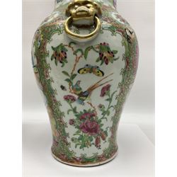 Pair of 19th century Chinese Famille Rose vases and covers, each of baluster form with twin gilt lion mask ring handles to shoulders, the flattened domed covers with gilt temple lion finials, each decorated with alternating reserves of bijin and attendants, and birds and butterflies amongst blossoming peonies, against a gilt ground profusely decorated with stylised scrolls, H32.5cm