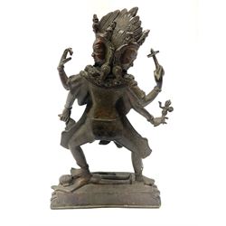 Eastern Bronzed figure modelled as the deity Kali with eight arms and three faces stood on shiva's chest, upon stylised locus base H28cm