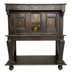 18th century and later oak court cupboard, lunette carved frieze over panelled front enclosed by two doors, inlaid with floral urn and two chequered lozenges, carved masks over tapering supports carved with feather decoration on lower tier, turned feet