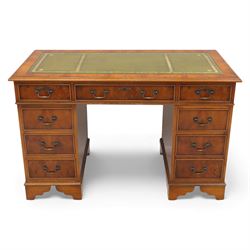 Late 20th century yew wood nine drawer writing desk, rectangular top inset with gilt-tooled green leather, above an arrangement of nine drawers with brass swan-neck handles, raised on bracket feet