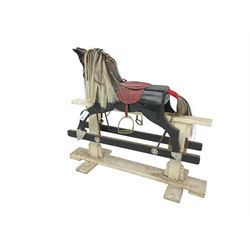 20th century black painted rocking horse on white painted trestle base, fitted with saddle and stirrups 