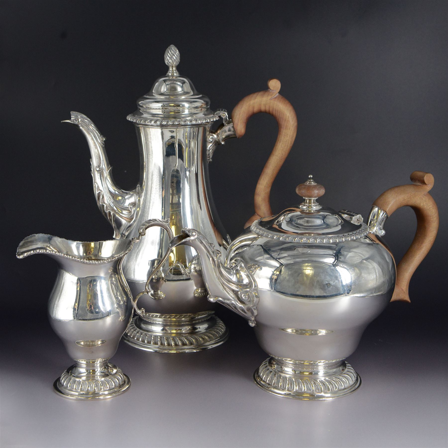 Modern three piece silver tea service, comprising coffee pot, teapot and milk jug, each of spherical form, upon circular domed foot, the teapot and coffee pot with wooden handles, the teapot with wooden finial, hallmarked Bryan Savage, London 1975, coffee pot H29cm