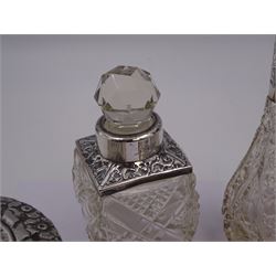 Two silver mounted dressing table jars, one in the form of a heart, both with embossed silver covers and cut glass bodies, hallmarked, together with two smaller examples, one set with mother of pearl, three silver mounted glass scent bottles, including an example with prunus blossom decoration, stamped Sterling, tallest bottle H17cm