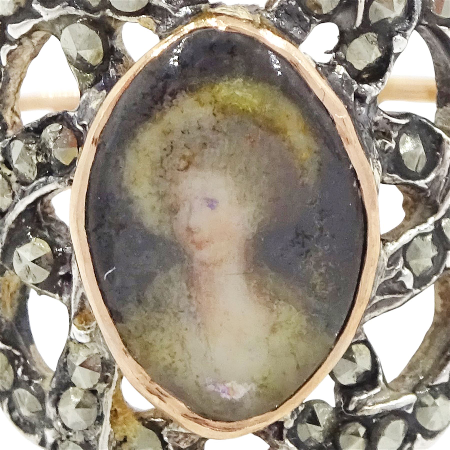 19th century gold and silver marcasite portrait ring, set with an oval miniature of a woman on ivory, under a glazed panel, with a marcasite and red stone set crossover surround, with pierced gold shoulders and reeded shank. This lot has been registered for sale under Section 10 of the APHA Ivory Act