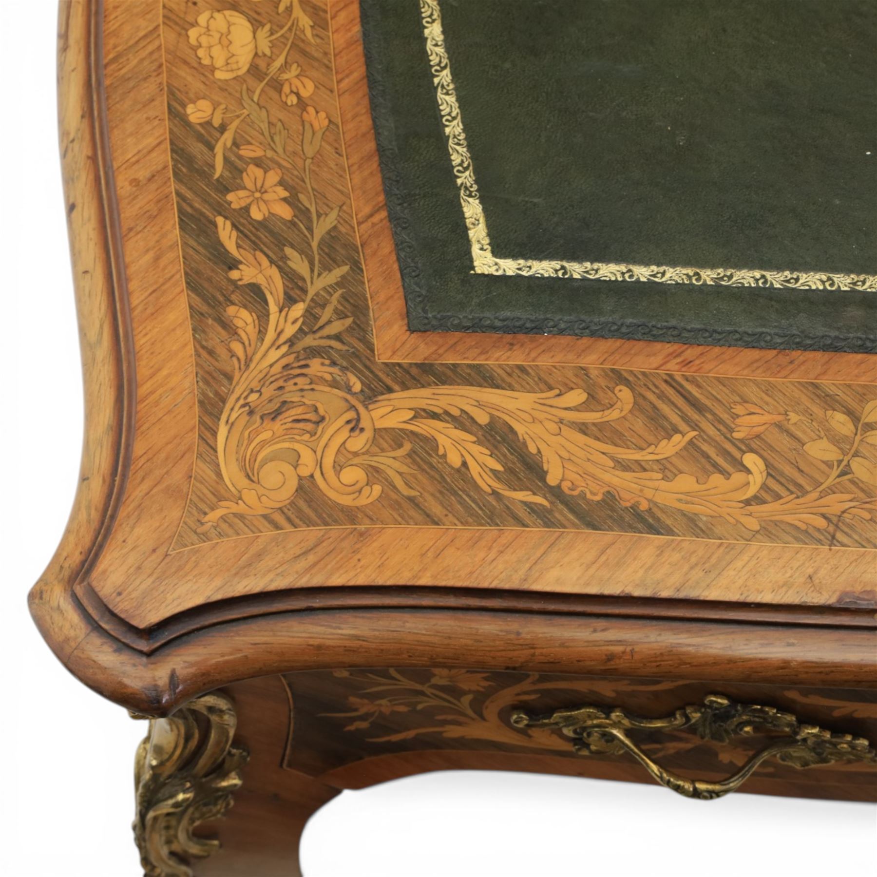 Late 19th century French kingwood and marquetry bureau plat, the serpentine rectangular top with green leather inset writing surface within crossbanded and foliate marquetry border, above a shaped frieze fitted with three drawers with floral marquetry panels and gilt metal handles, upon cabriole supports with applied gilt metal mounts and sabots