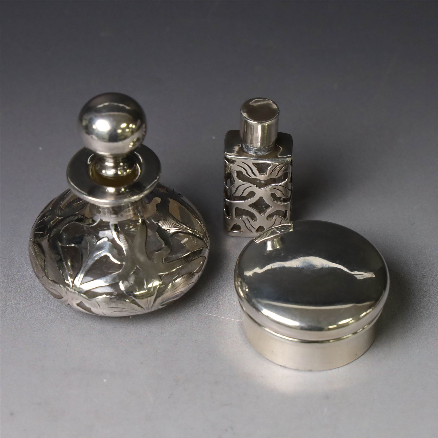 Two early 20th century silver pill/patch boxes, together with two glass perfume bottles with silver overlay and stoppers, all stamped or hallmarked, smallest box D2cm, largest bottle H7cm