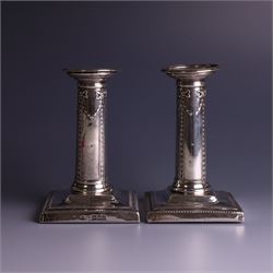 Pair of late Victorian silver mounted candlesticks, the stems embossed with classical ribbon and swag design, upon weighted stepped square bases, hallmarked London 1899, maker's mark worn and indistinct, H12cm
