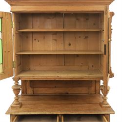 Late 19th century French pine dresser with stained glass upper section, the upper section with projecting cornice with fluted and scrolled details, enclosing a shelved interior, supported on turned front uprights, the lower section with frieze drawers and cupboard doors, raised on bun feet