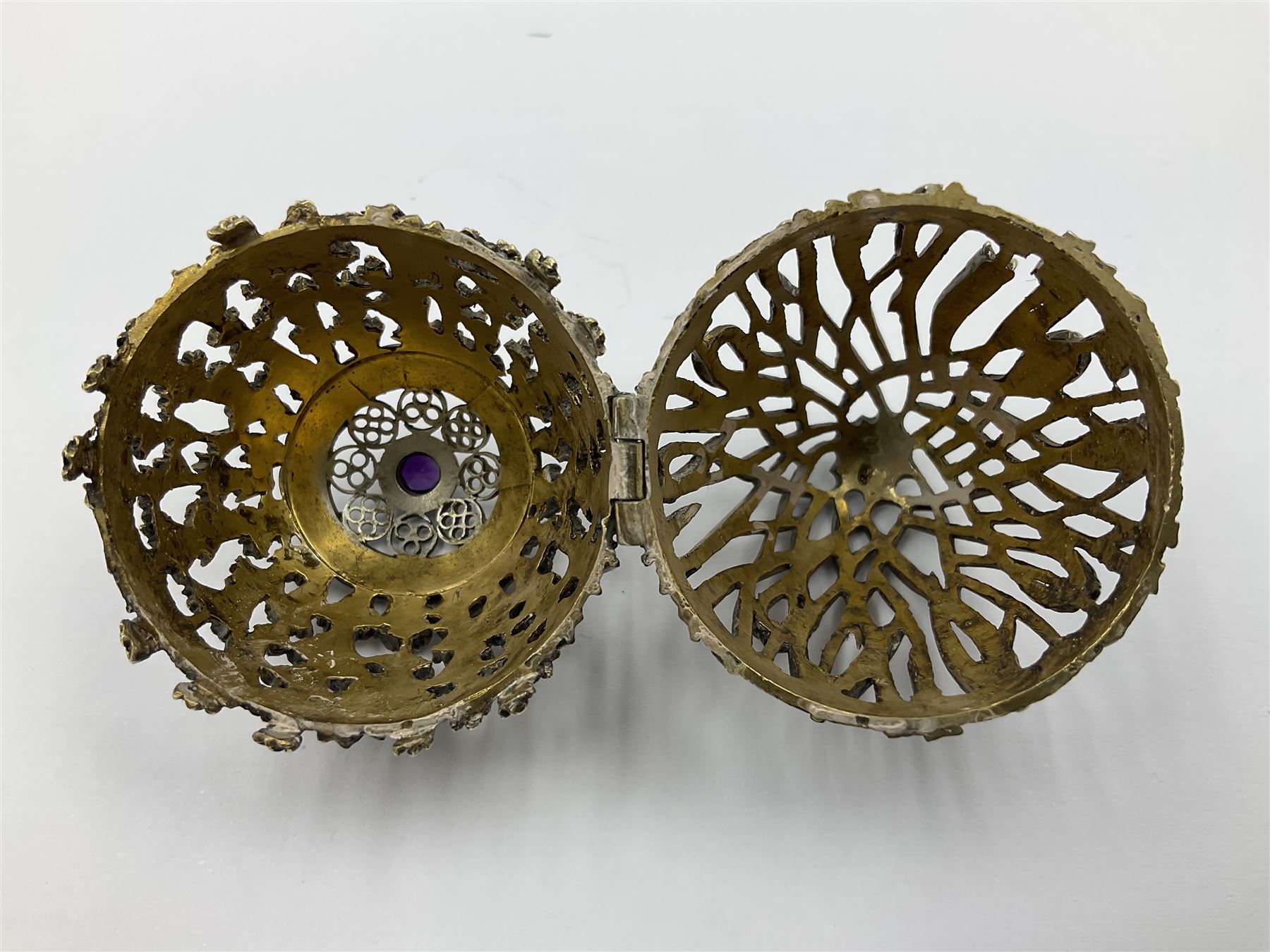 Modern silver limited edition Easter egg, no. 70/500, the gilt openwork body decorated with cascading bluebells and hinged cover with pierced circular panel set with a single faceted purple stone, opening to reveal a gilt interior, upon silver stand with three scrolling pad feet, each hallmarked St James House Company, London 1981, height including stand 8cm