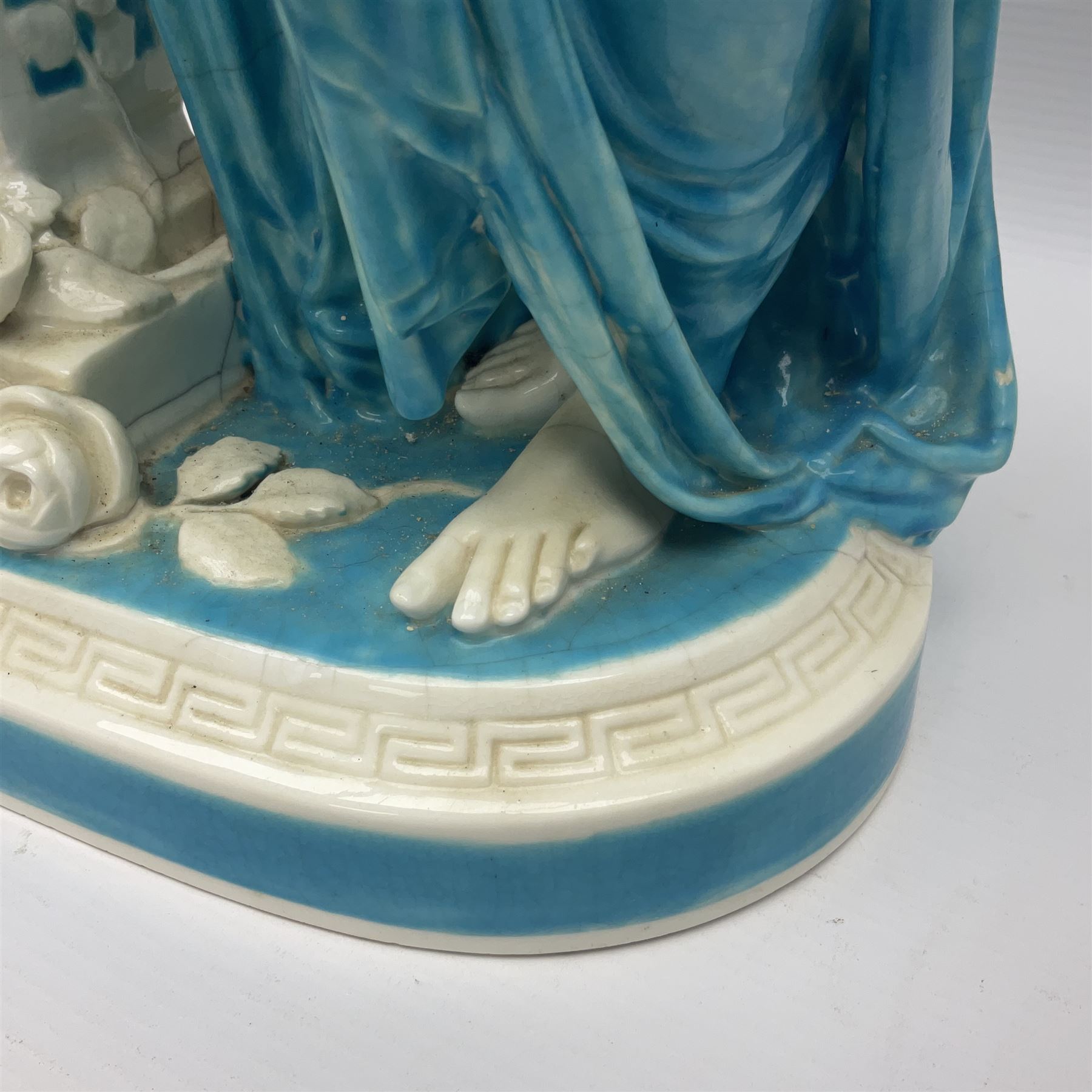 Rare 19th century Minton turquoise glaze majolica 'The Reader' flower holder, after Albert Carrier-Belleuse, modeled as a maiden in classical drapery reading whilst leaning against the pillar back of the helmet shaped cistern detailed with a caryatid and floral swags, the whole upon an oval plinth with Greek key border, with impressed marks beneath, H44cm