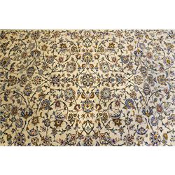 Central Persian Kashan hand-knotted carpet, ivory field decorated with an all-over scrolling floral vine design incorporating stylized palmettes, rosettes, and foliate sprays in the Shah-Abassi style enclosed by a series of floral vine borders and multiple narrow guard stripes, cotton fringe ends 