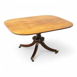 Regency figured mahogany breakfast table, figured rectangular tilt-top with rounded corners and rosewood banding, on turned column with four out-splayed supports with brass cups and castors 