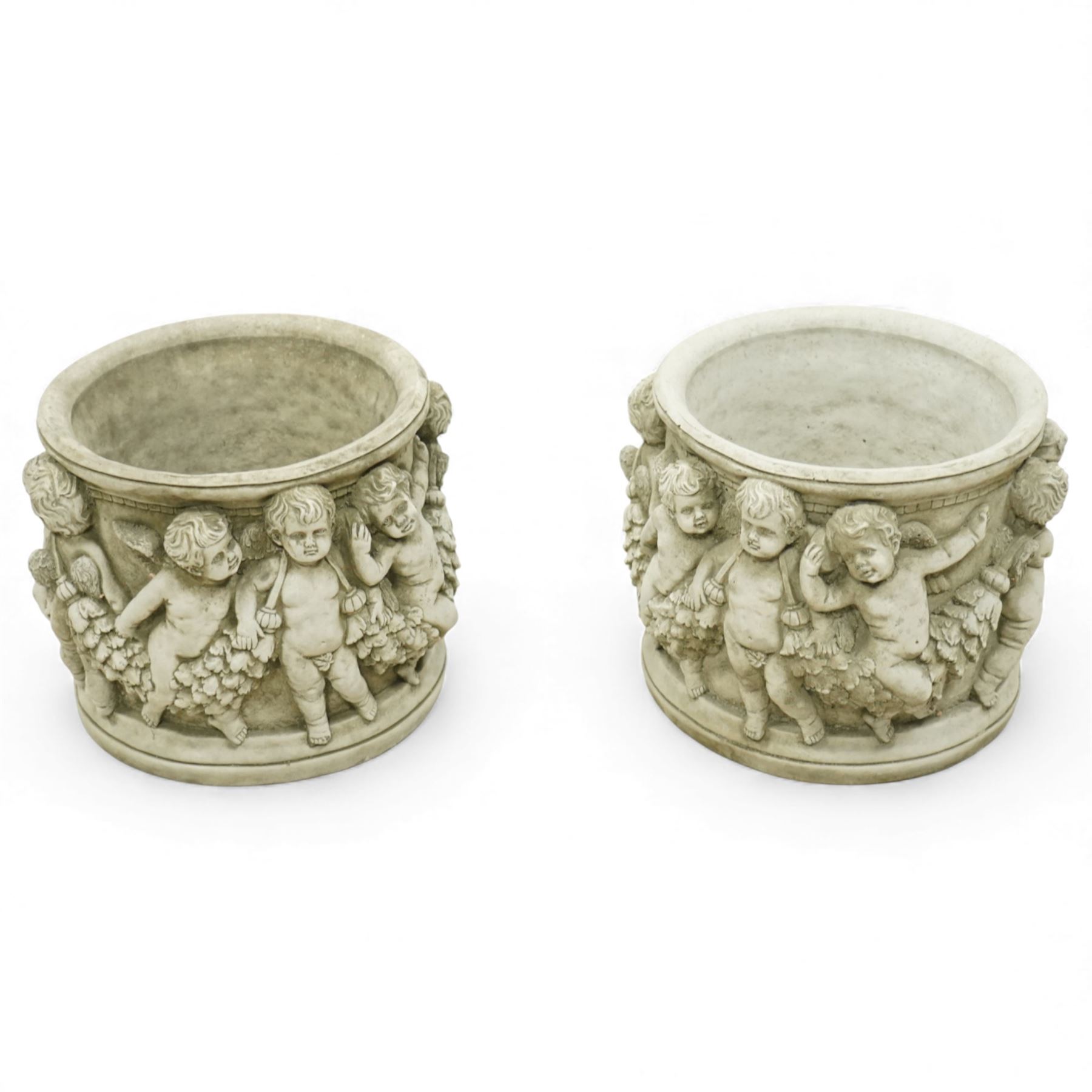 Pair of modern cast stone garden planters, circular tapering bodies moulded with cherubs in high relief among foliage and fruiting vines, in a weathered stone finish