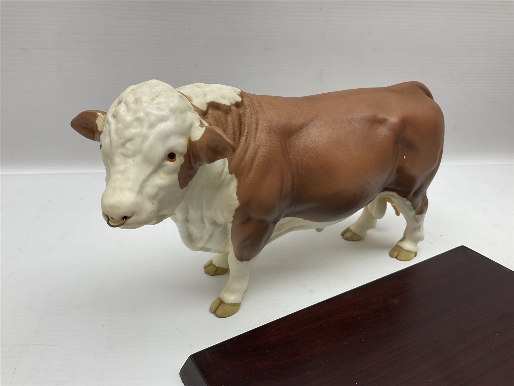Beswick matte Hereford Bull, with stamped mark beneath, on wooden plinth, together with a limited edition Bradford Exchange John Wayne model, tallest H36cm