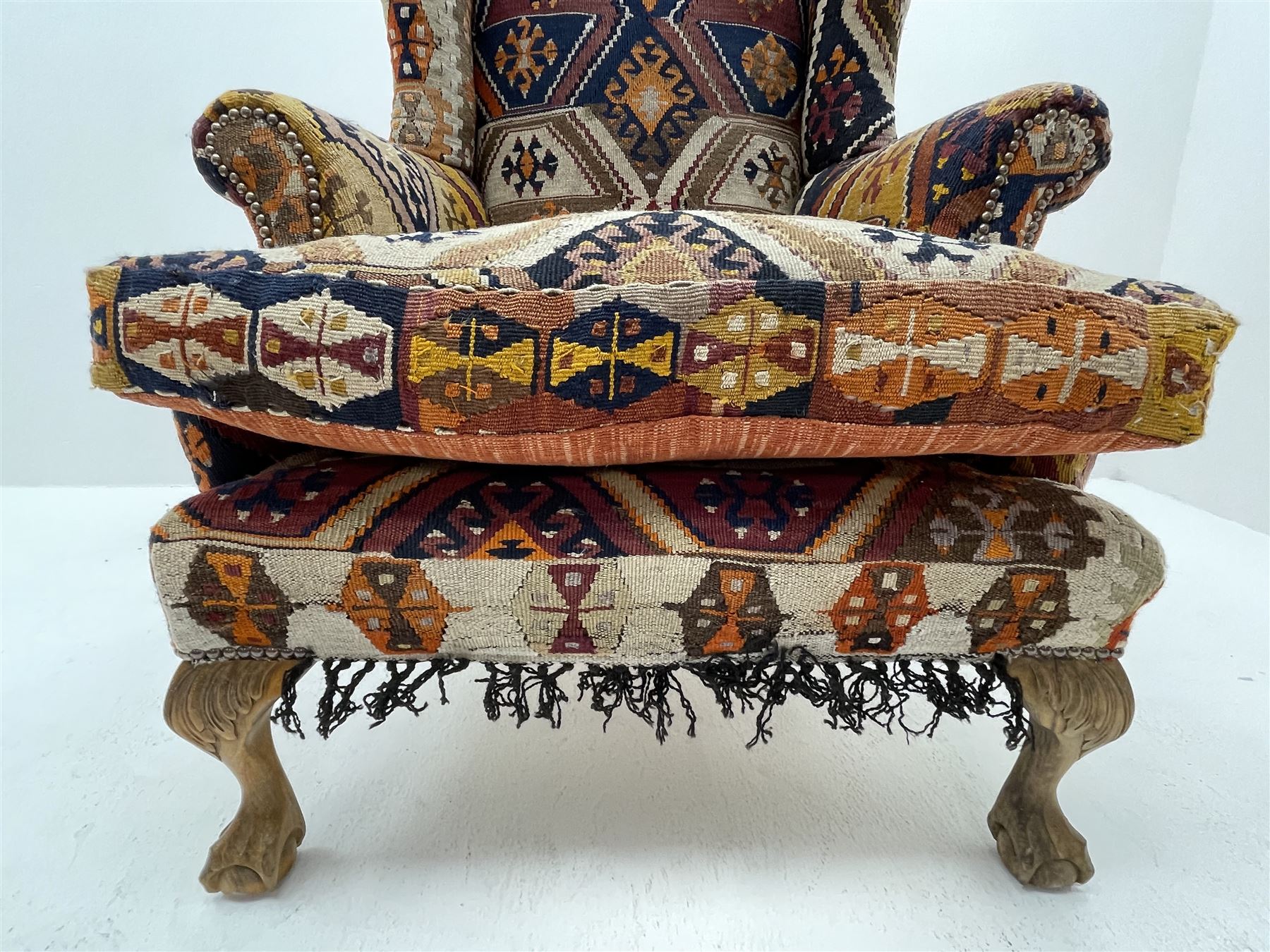 Late 20th century beech framed wingback armchair, sprung seat and back upholstered in kilim cover, acanthus carved cabriole supports with ball and claw feet