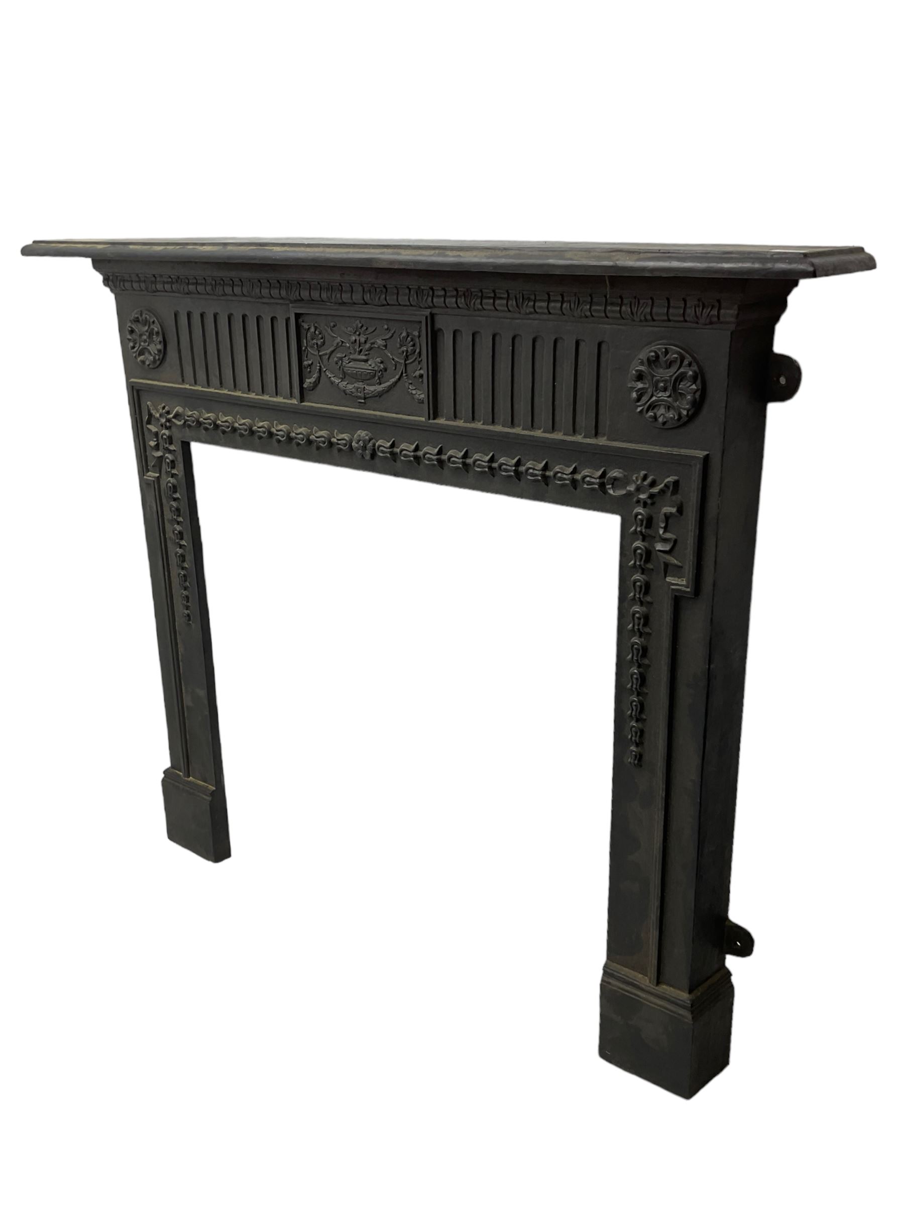 Adam design - cast iron fire surround, moulded rectangular mantel over central foliate urn and vertical flutes, flanked by C-scroll floral roundels, the aperture decorated with trailing bellflowers