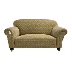 Early 20th century two seat sofa, upholstered in foliate patterned fabric, on compressed bun feet with castors