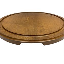 Acornman - oak chopping board, circular form with moulded edge and sunken groove, the side carved with acorn signature and recessed handles, by Alan Grainger, Brandsby