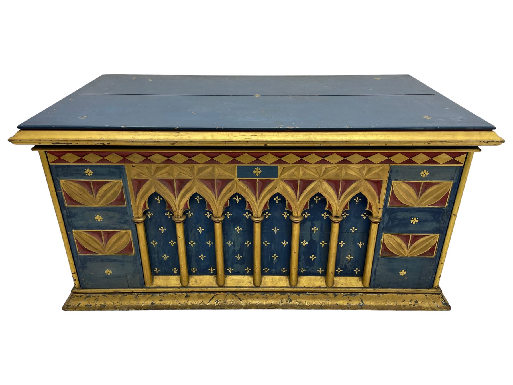In the manner of William Burges - mid-to-late 19th century English Gothic Revival pine altar or console table, in blue and red paint with water gilding, the moulded rectangular top over six pointed arches with turned column supports, the front carved with a single row of lozenges and incised stylised motifs
