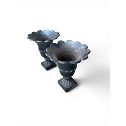 Pair of Victorian large scale cast iron garden urns, flared petal shaped rim with tapering waist, gadrooned base on square plinth, finished in black paint