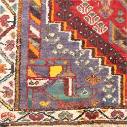 Northwestern Persian village rug, madder red field, with serrated central panel enclosing three linked lozenge medallions, polychromed spandrels, ivory border, and geometric guard stripes  