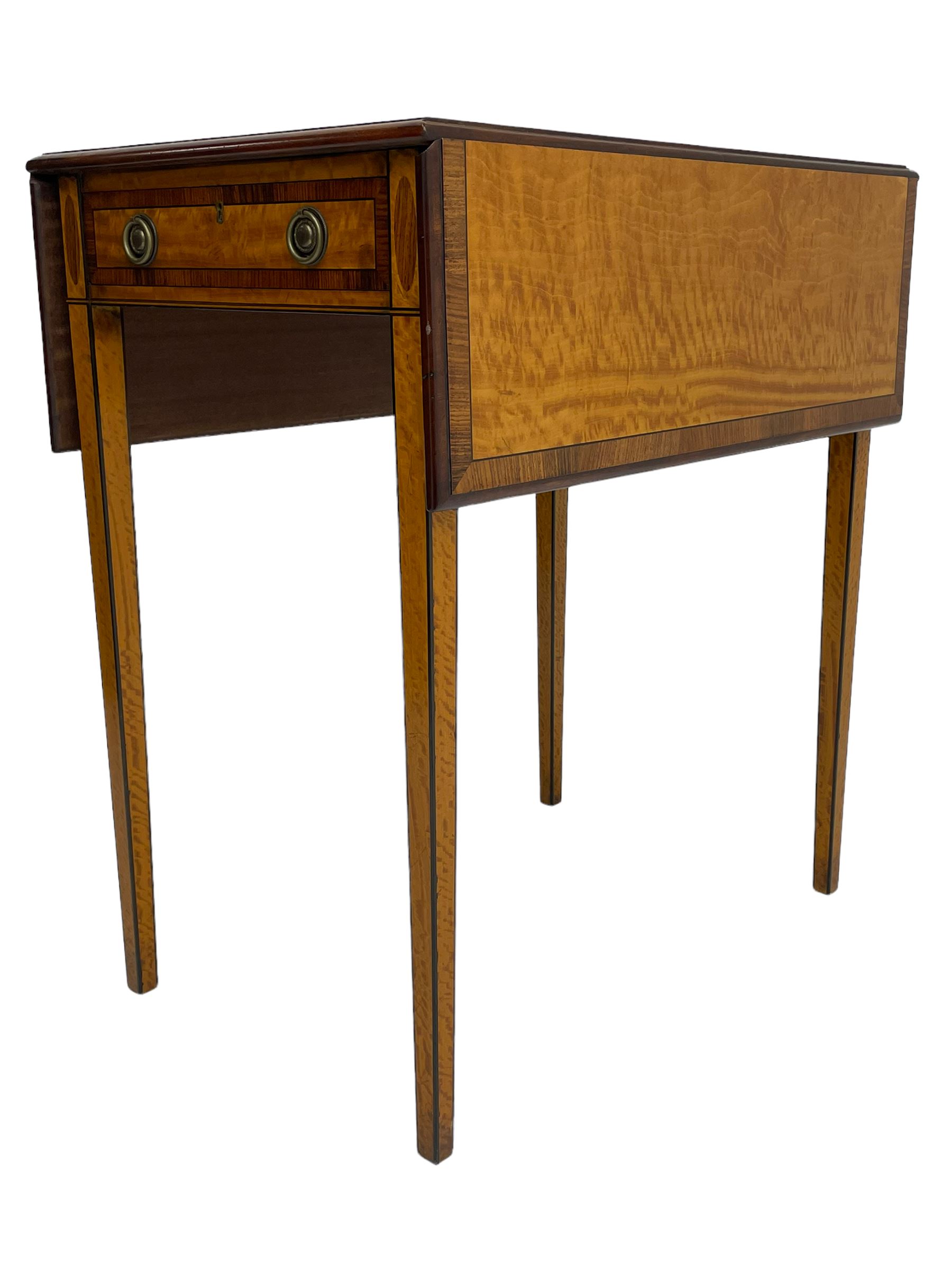 Mid-to-late 20th century Sheraton style satinwood Pembroke table, the drop leaf top with segmented veneers and central oval panel with ebony stringing, crossbanded in rosewood and with edge moulding, single short drawer to one end and faux drawer to other, square tapering supports