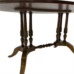 Early 20th century walnut coffee table, oval dished top with sunburst matched veneer, raised on twin cluster columns united by turned stretcher base on splayed supports
