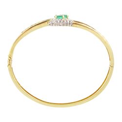 14ct gold emerald and diamond crossover bangle, two oval cut emeralds with round brilliant cut diamond surround, with channel set calibre cut emerald shoulders, stamped 585