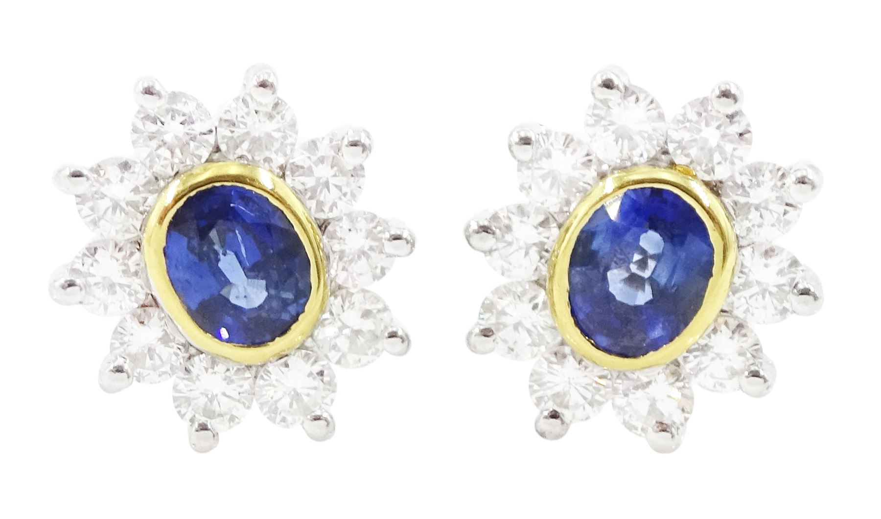 Pair of 18ct white and yellow gold oval cut sapphire and round brilliant cut diamond cluster stud earrings, London 1991, total sapphire weight approx 0.60 carat, total diamond weight approx 0.60 carat