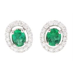 Pair of 18ct white gold emerald and diamond cluster earrings, each stud set with a single ...