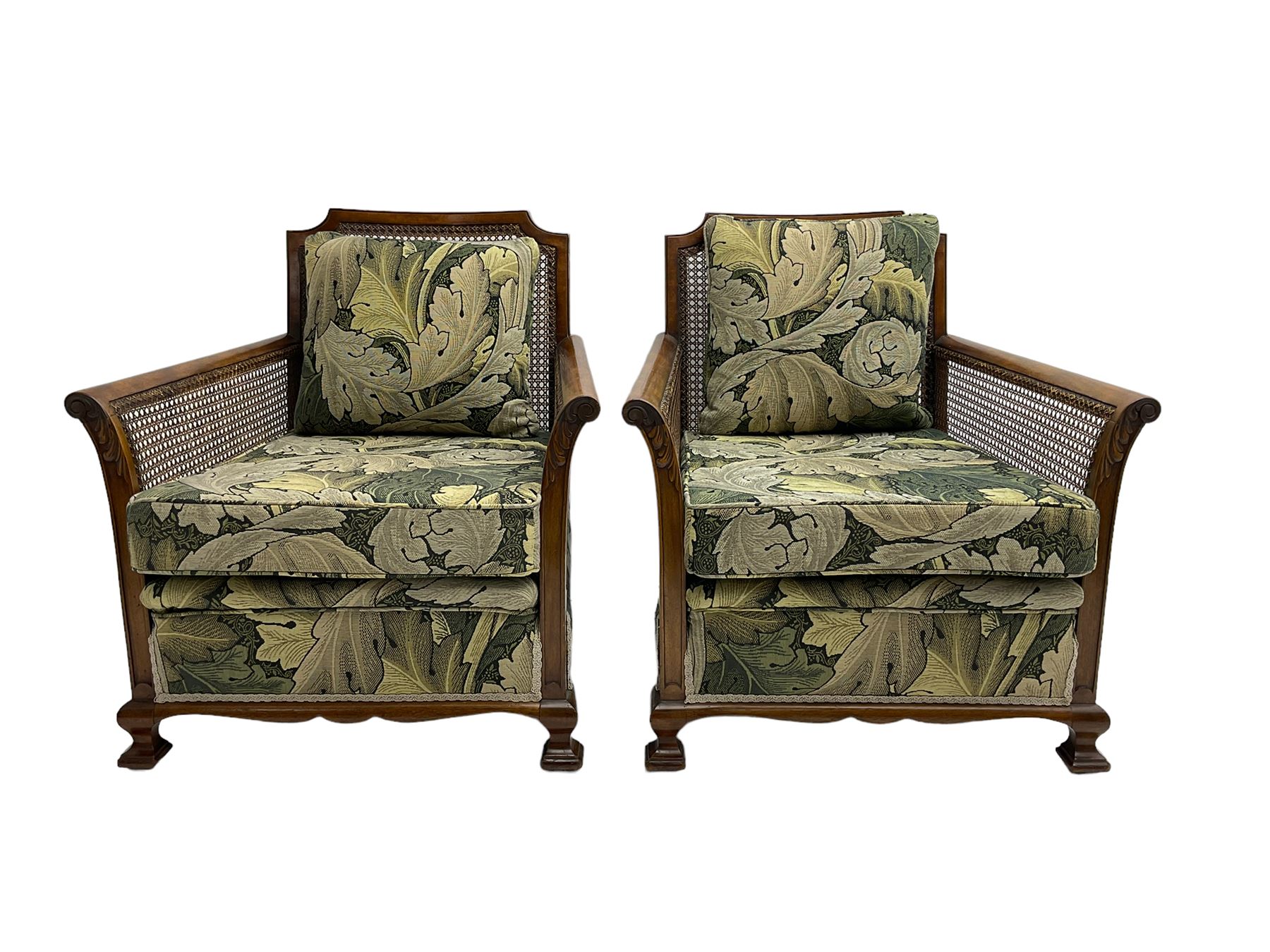 Early 20th century bergère lounge suite, mahogany framed with cane work back and sides, acanthus scroll carved uprights - three seat sofa (W167cm, H82cm, D83cm), and pair matching armchairs (W78cm), loose cushions upholstered in acanthus leaf scroll fabric with scatter cushions