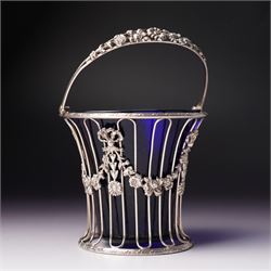 Edwardian pierced silver sugar basket with swing handle and blue glass liner H9cm London 1906 Maker Haseler Bros. and another decorated with floral swags Chester 1912 Maker  (2)