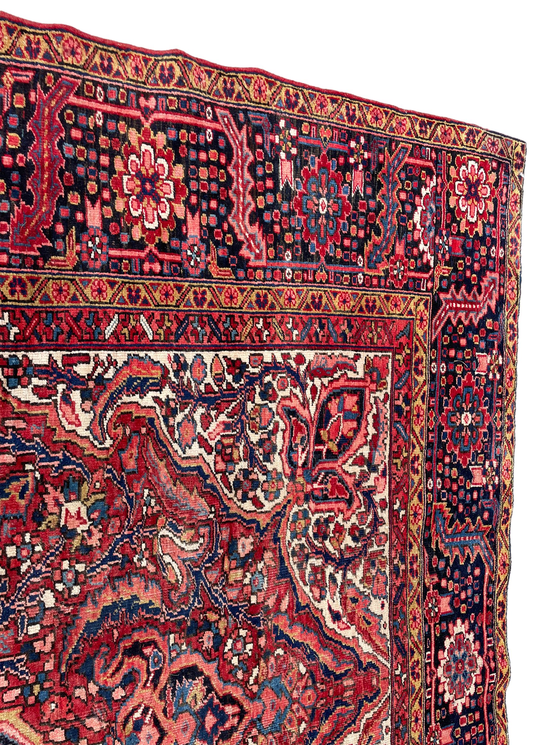 Antique Persian coral ground carpet, the large central floral pole medallion with extending foliate designs, the thick guarded indigo border with repeating flower heads and circles
