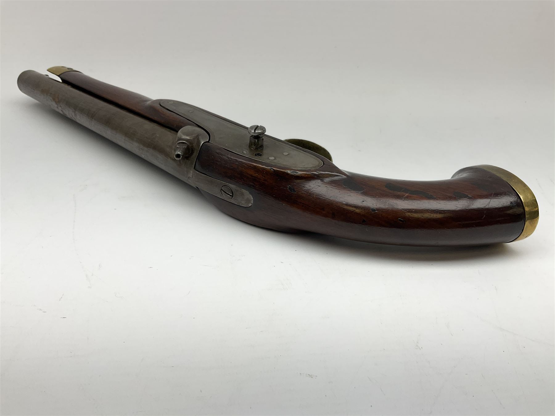 Early 19th century percussion cap cavalry pistol with round 23cm unsighted barrel, borderline engraved action lock (lacking hammer), walnut full stock with heavy brass furniture, iron lanyard ring to the flat butt cap and long flat retaining spring below fore-end for captive ramrod (missing) L41cm overall