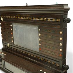 Victorian wall-mounted oak and walnut cased scoreboard,  moulded top, with a name stencilled in the frieze ‘J. Ashcroft, Victoria Street, Liverpool’, the board with chalk panel in the centre for recording scores, sliding panels on both sides for the various games of Billiards and Snooker, two numbered rotating arms with adjustable sliding score keepers, the base section with 5 apertures on each side, and coloured ivory roundels, all with glass front for viewing the tokens inside, with drawers beneath, the centre has a long glass panel for storing billiard balls, circa 1870 This item has been registered for sale under section 10 of the APHA Ivory Act Reference UNEGEBLB
