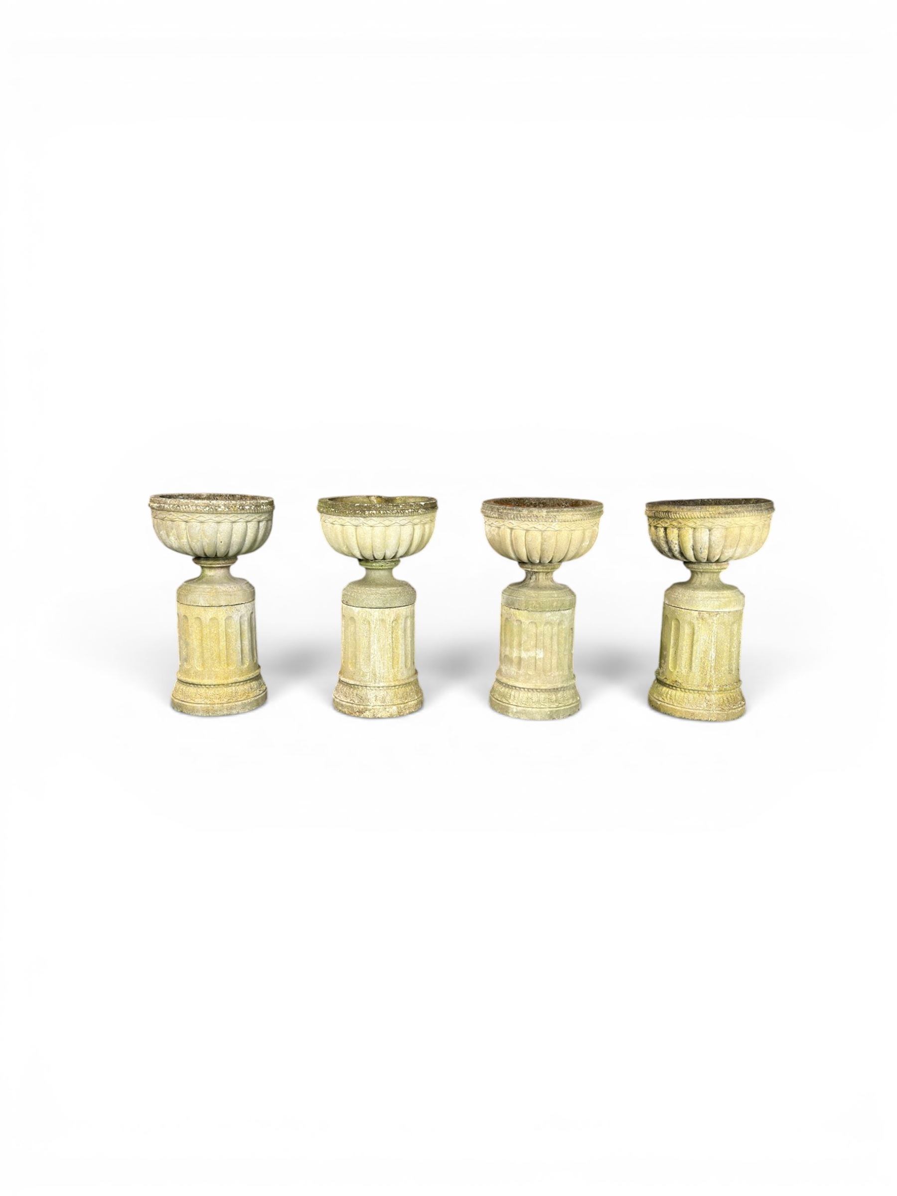 Four 20th century good quality weathered cast stone pedestal urns, circular lobed bowls with rope twist and lattice border, raised on squat base with fluted columns