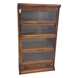 Early 20th century oak stacking library bookcase, four sections enclosed by hinged and sliding glazed doors, fitted with single drawer 