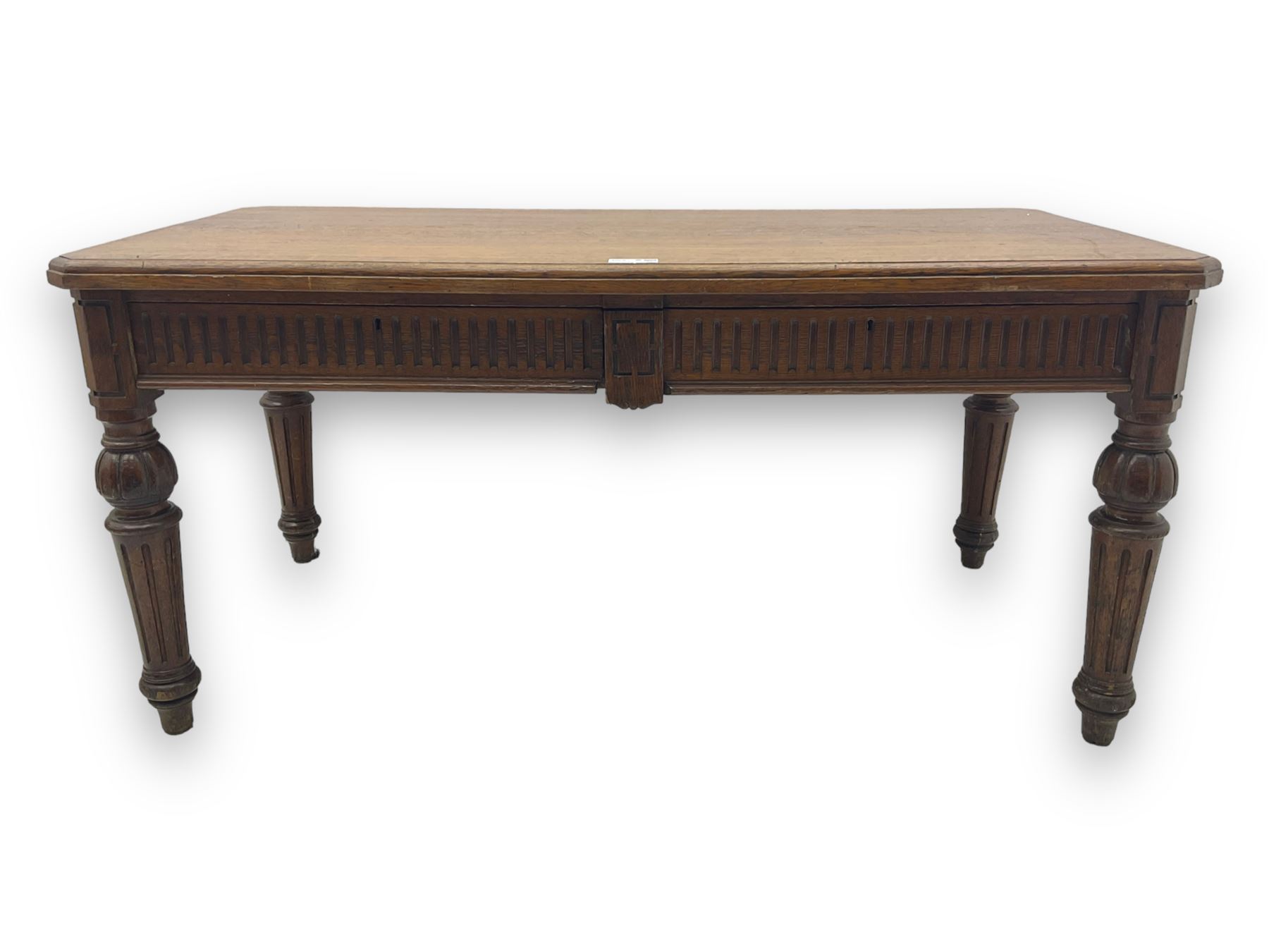 Late 19th century oak library table, moulded rectangular top with canted corners, fitted with two frieze drawers with fluted facias, on lobe carved and fluted turned supports 