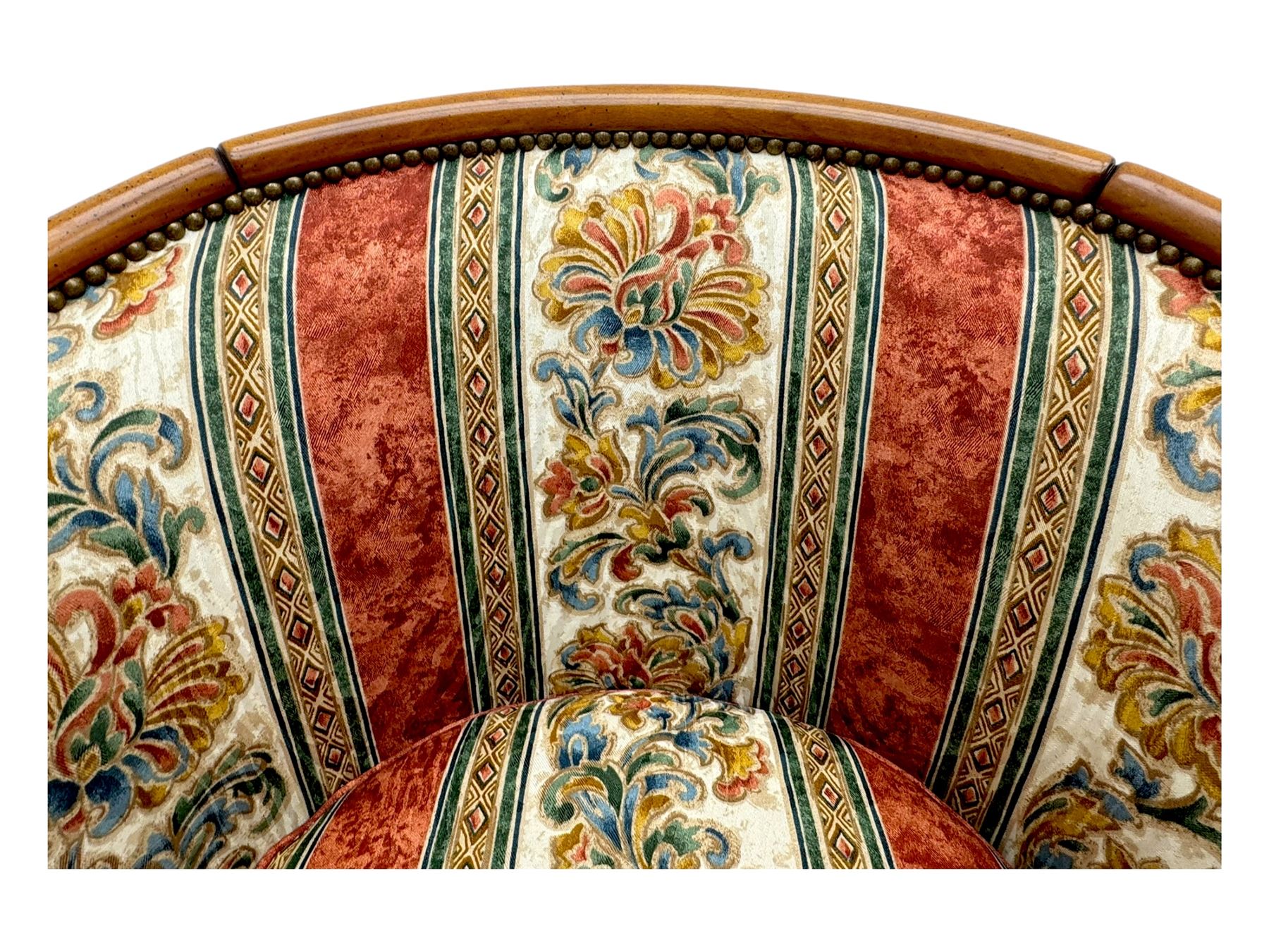 Pair of cherry wood framed tub-shaped armchairs, upholstered in striped floral fabric with brass stud trim, carved walnut frame with fluted supports capped with pinecone finials, on turned feet
