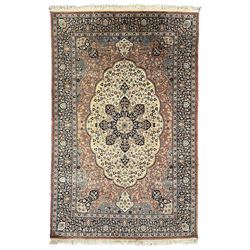 Persian Kashan peach ground rug, central rosette medallion within a field of trailing foliage and flower heads, repeating scrolling border decorated with stylised plant motifs