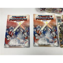 Four 1980sTransformer G1 - Optimus Prime 1984; DinoBot Sludge (Diplodocus) 1984; Cyclonus 1986; and Runamuck 1986; with paperwork; seven Bandai Robo Machines Robots/Transformers; almost fully stocked Panini Sticker album; two annuals; three comics; two posters; and Ladybird story book