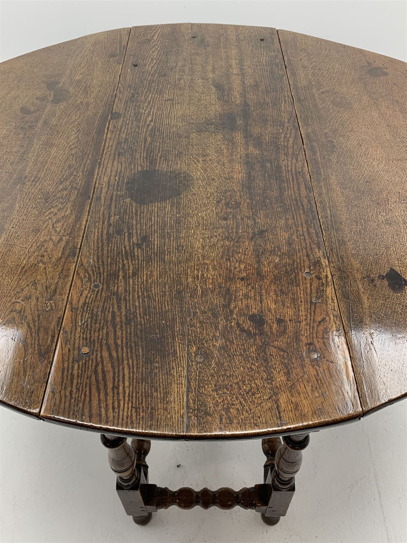 Late 17th century William & Mary oak drop leaf dining table, oval drop leaf top, single drawer to one end, gate action base, turned supports joined by bobbin turned stretchers, 121cm x 135cm, H75cm (open)