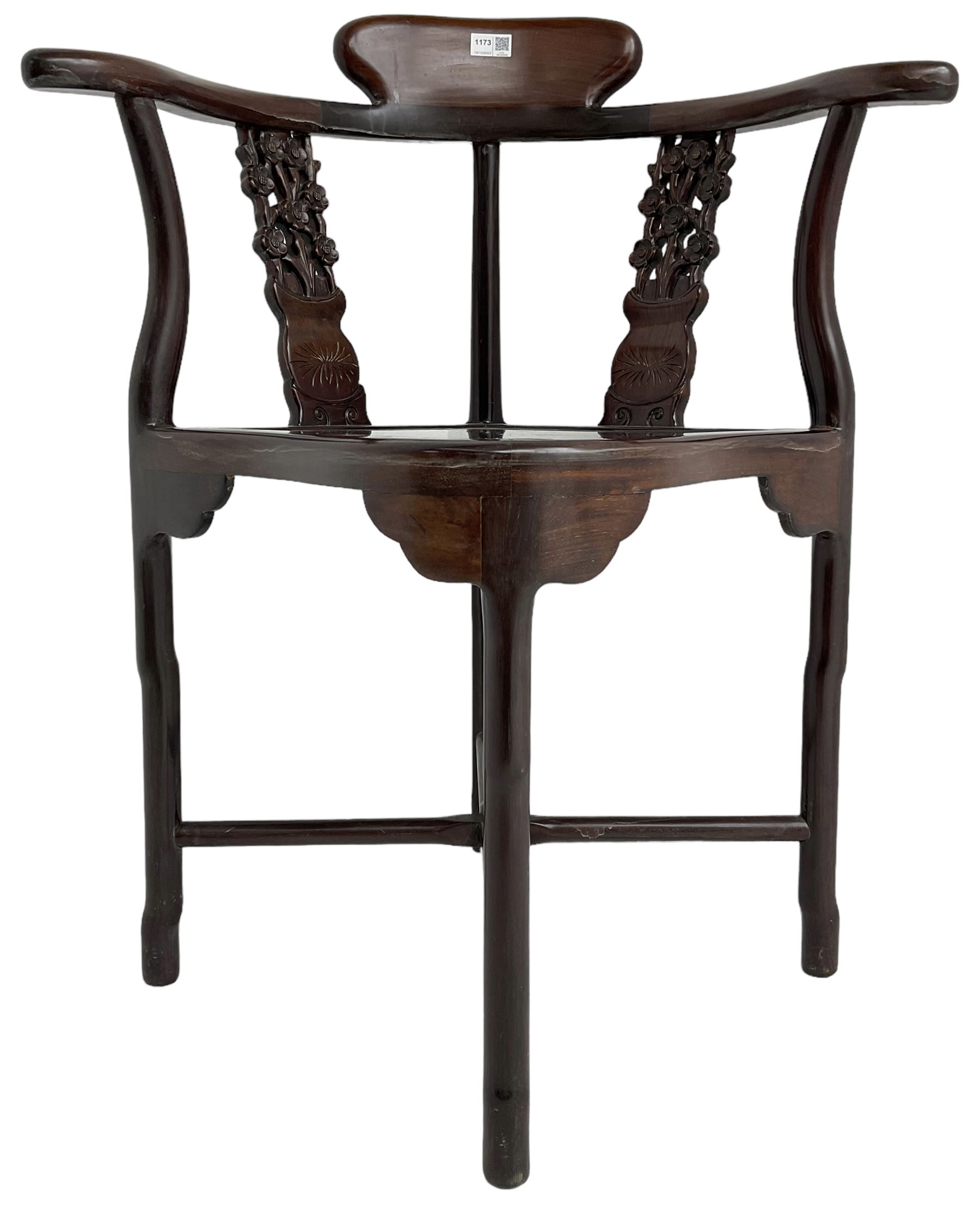 Chinese carved hardwood corner chair, outswept arms over pierced and carved floral splats, raised on shaped cylindrical supports united by X-stretcher