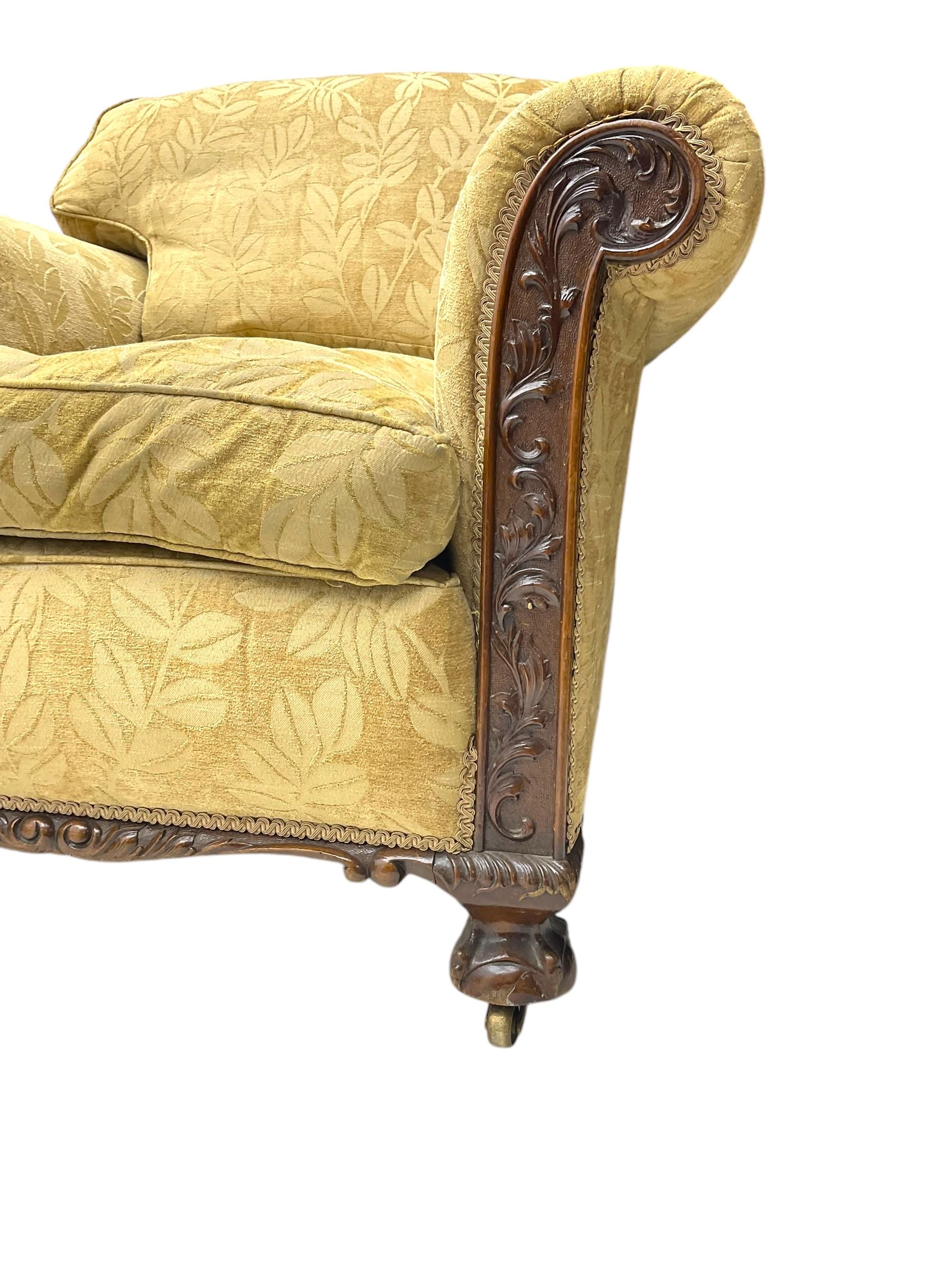 Early 20th century mahogany framed three-piece lounge suite - three-seat camelback sofa (W203cm, D105cm); pair of matching armchairs (W95cm, D96cm); upholstered in neutral foliate pattern fabric, carved with trailing leafy branches, ball and claw carved feet with brass castors 