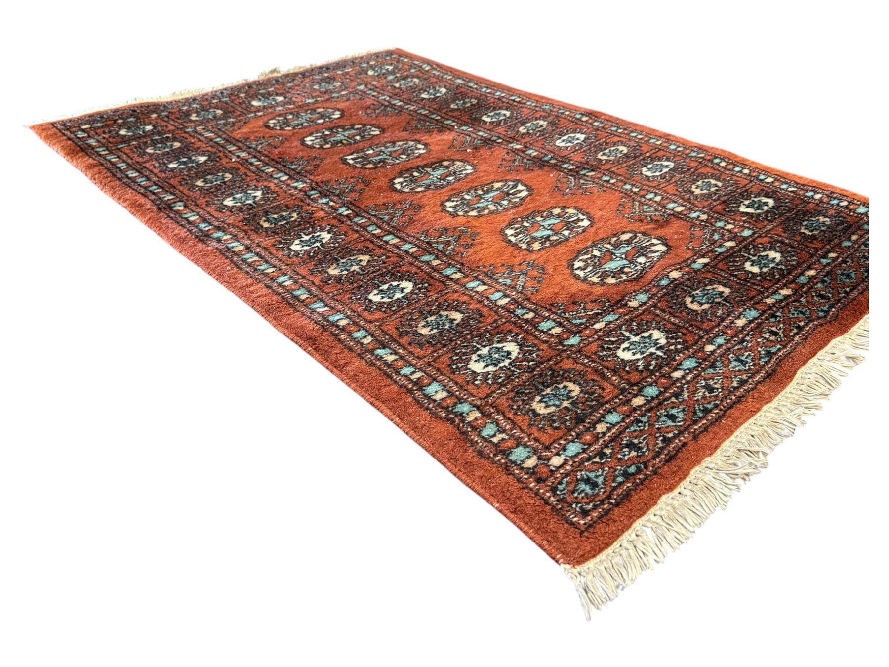 Pair of rugs one Persian hamadan rug central stepped medallion enclosing geometric motifs in ivory and brown, framed by a cream border with scrolling palmettes and fringed ends (H 156cm W 105cm), one Pakistani Bokhara rug rust red ground with repeated Tekke gul motifs within rosette and lozenged borders, fringed ends (H 98cm, W 65cm)