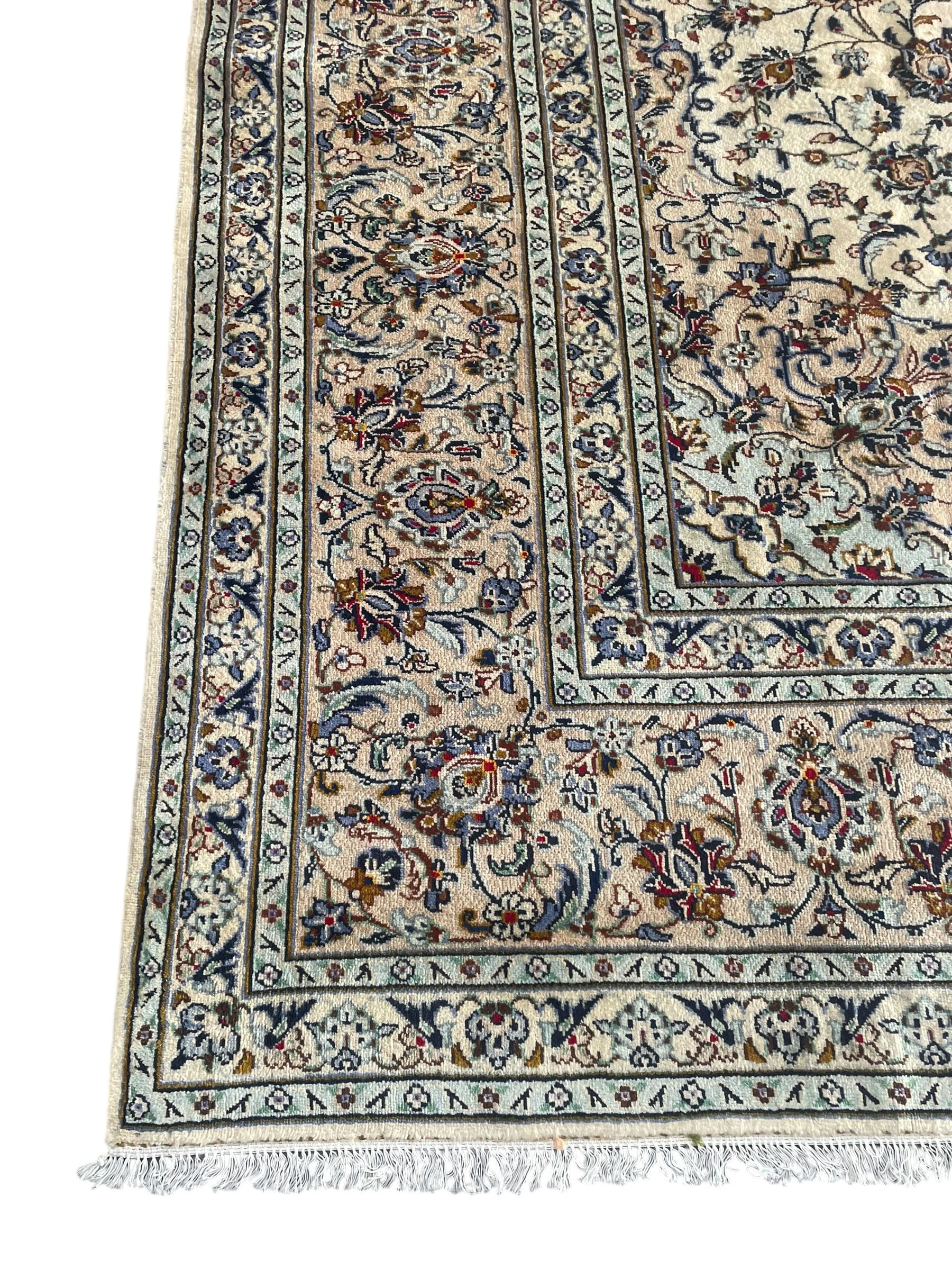 Persian Kashan ivory ground carpet, the field decorated with interlacing foliate branches and stylised plant motifs, scrolling border decorated with repeating palmettes, within floral pattern guard bands