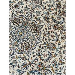 Persian Kashan ivory ground carpet, central pole medallion surrounded by swirling leafy branches and stylised plant motifs, scrolled foliate spandrels, the main border decorated with scrolling pattern and repeating palmettes, within floral patter guard stripes 